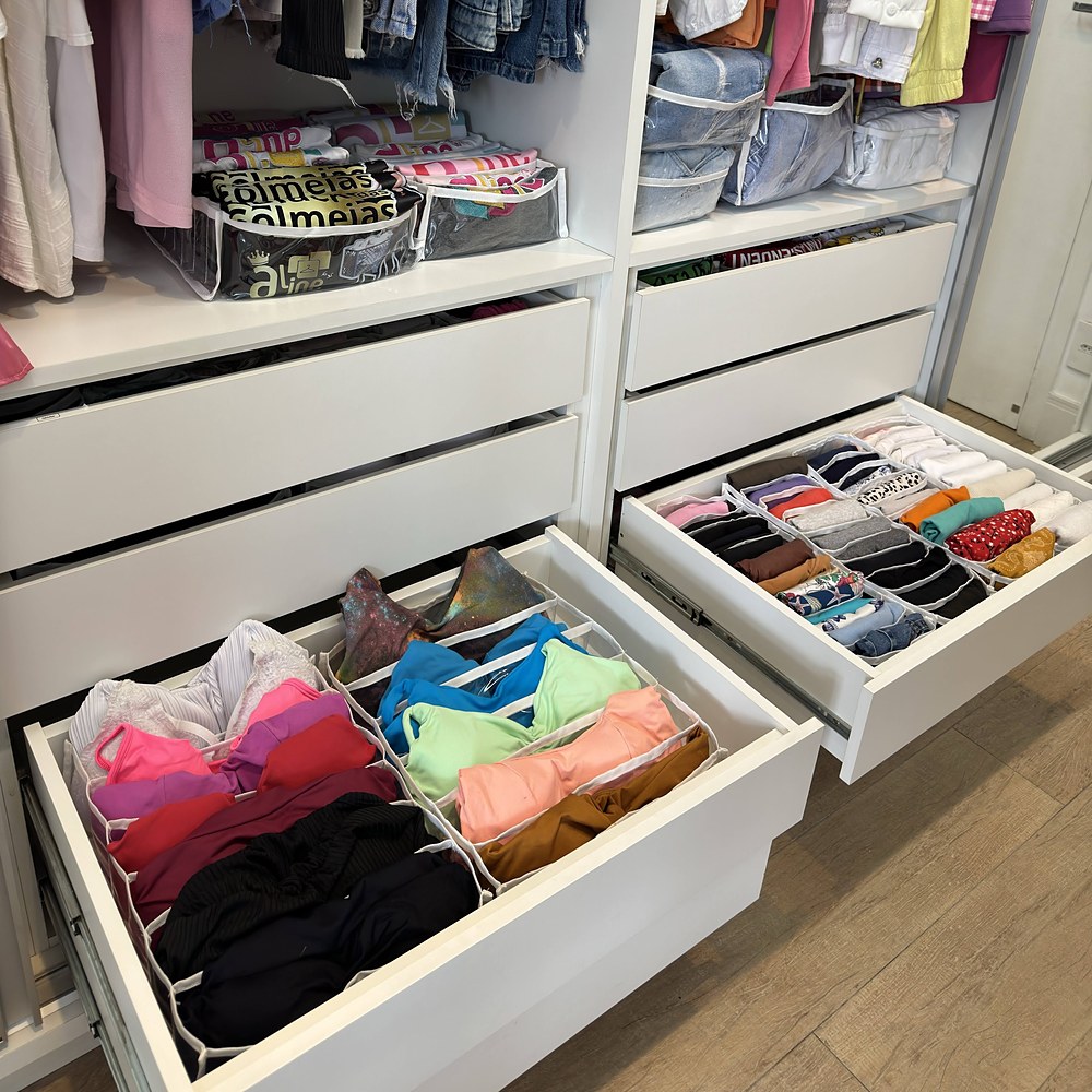 Guarda-roupa com duas gavetas abertas: tops, biquínis, calcinhas e meias em colmeias organizadoras; na prateleira, camisetas e calças jeans também em colmeias organizadoras